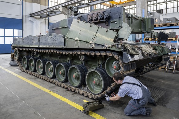 Ein Mechaniker wartet die Raupen an einem Panzer vom Typ Leopard 2 in einer Wartungshalle der RUAG, am Montag, 20. Maerz 2023, in Thun. (KEYSTONE/Peter Schneider)