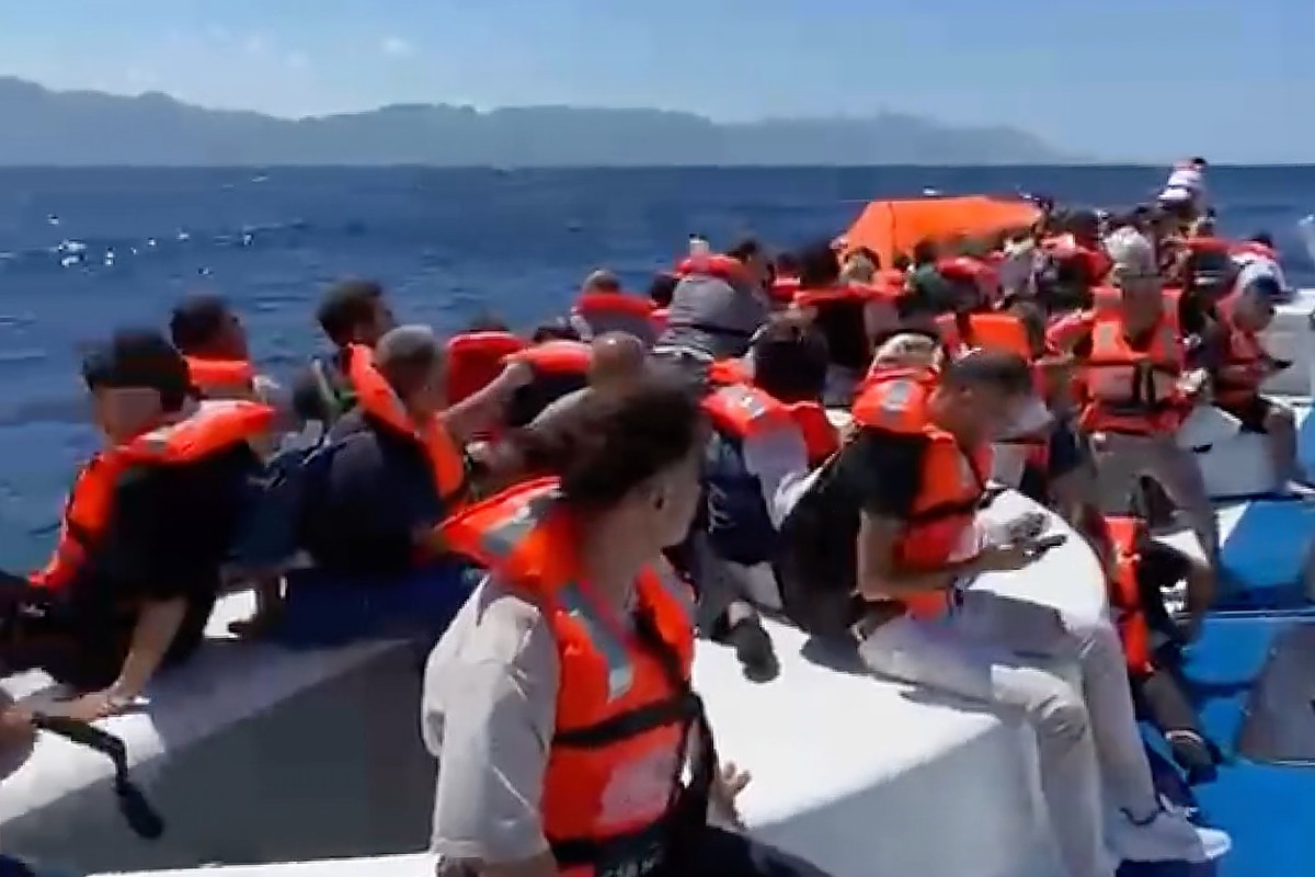 In this frame grab from a video, passengers wearing life jackets wait atop a capsized passenger vessel to be rescued off the coast of Girne, in the Turkish-occupied northern part of Cyprus, Sunday, Au ...