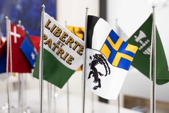 Faehnchen mit den Kantonswappen der Kantone Waadt, Graubuenden und St. Gallen, vorne von links, und weiterer Kantone stehen auf einem Tisch, waehrend einer Medienkonferenz ueber die Stellungnahme der  ...