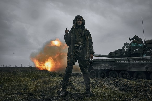 A Ukrainian soldier gestures as a captured Russian tank T-80 fires at the Russian position in Donetsk region, Ukraine, Tuesday, Nov. 22, 2022. (AP Photo/LIBKOS)