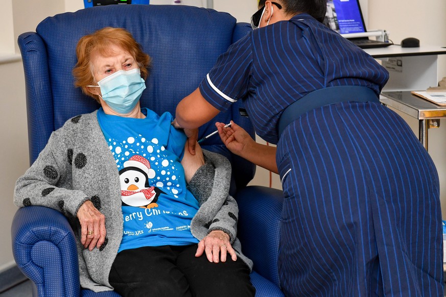 epaselect epa08869595 Margaret Keenan (L), 90 years old, is the first patient in the United Kingdom to receive the Pfizer/BioNtech COVID-19 vaccine administered by nurse May Parsons, at the start of t ...