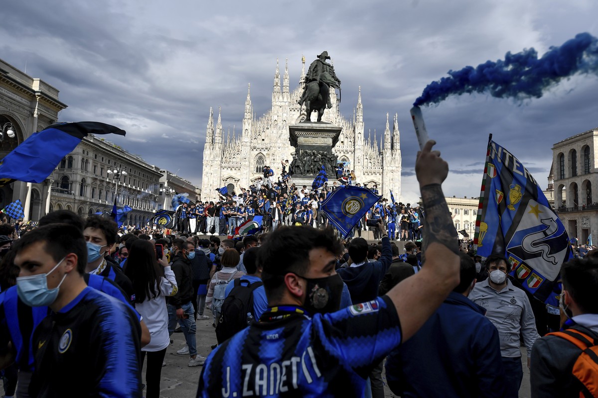 Inter Milan fans celebrate with flares and shout slogans in Piazza Duomo square in front of the gothic cathedral after Inter Milan won its first Serie A title in more than a decade after second-placed ...
