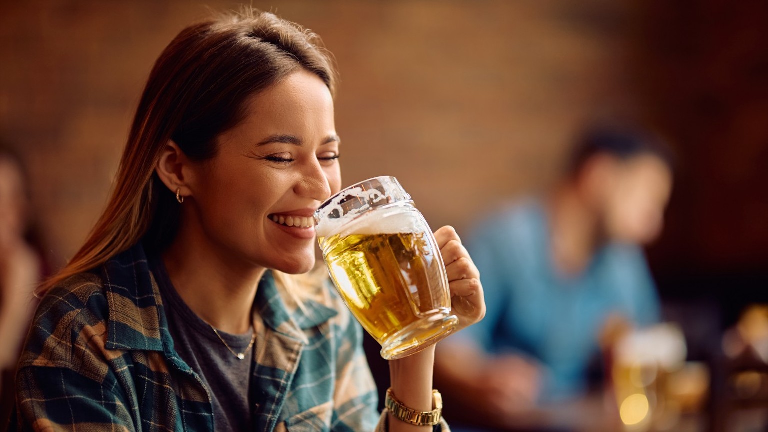 Young woman having fun while drinking beer in a bar.