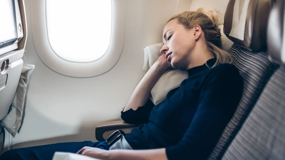 Eine Frau schläft im Flugzeug: Besonders entspannend ist das meistens nicht.