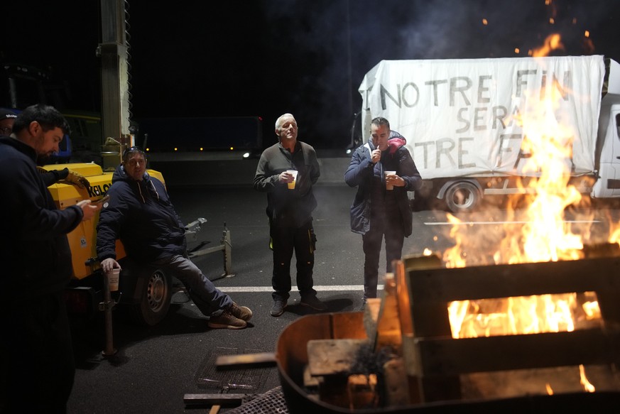 Farmers gather at a barbecue as they block a highway, Monday, Jan. 29, 2024 in Argenteuil, north of Paris. Protesting farmers were encircling Paris with tractor barricades and drive-slows on Monday, u ...