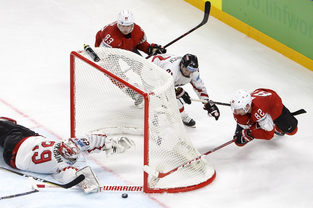 Austria's goaltender Bernhard Starkbaum, left, saves a puck past Switzerland's forward Joel Vermin #83, Austria's defender Dominique Heinrich #91 and Switzerland's forward Simon Mo ...