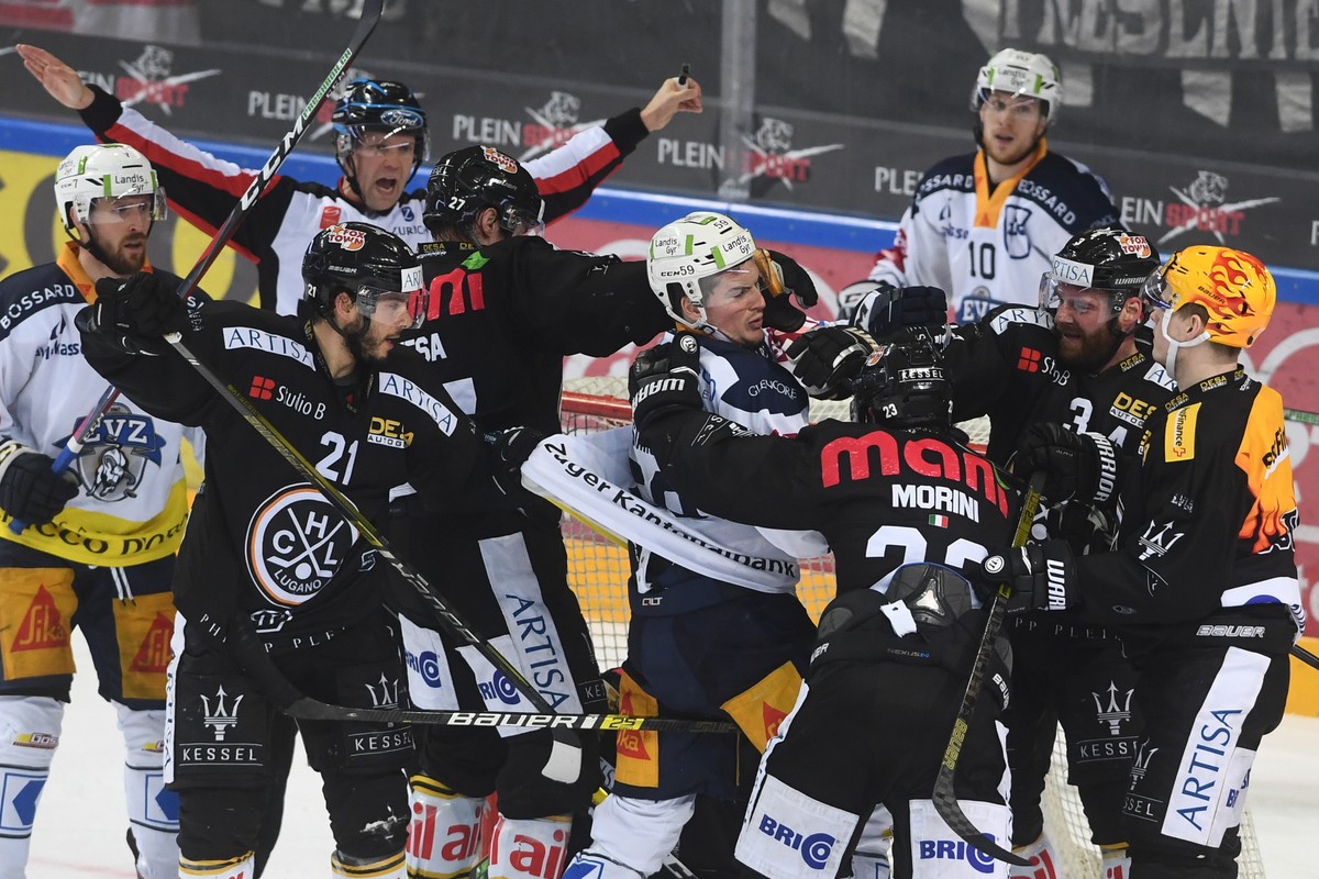 Zug's player Dario Simion, center, fights with Lugano's player Giovanni Morini, right, during the preliminary round game of National League Swiss Championship 2018/19 between HC Lugano and E ...