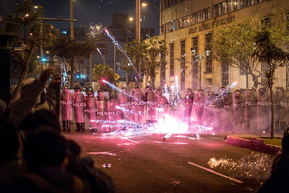 epa12457161 Peruvian police officers stand guard while blocking a flare near Congress during a demonstration against the new government of Jos