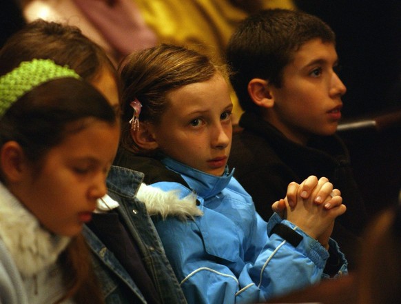 Junge Kirchenbesucher beten als Pier Giacomo Grampa, Bischof von Lugano, am Montag, 4. April 2005 in seiner Kathedrale von Lugano eine Gedenkmesse fuer den am Samstag verstorbenen Papst Johannes Paul  ...