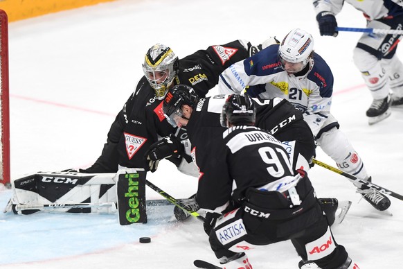 Lugano&#039;s goalkeeper Davide Fadani left fight for the puck with Ambri&#039;s player Brandon McMillan during the preliminary round game of National League A (NLA) Swiss Championship 2020/21 between ...