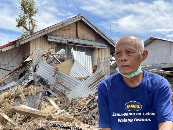 epa09653259 A handout photo made available by the Office of the Vice President of the Philippines (OVP) shows a villager standing next to a damaged house in the typhoon devastated city of Bais, Negros ...