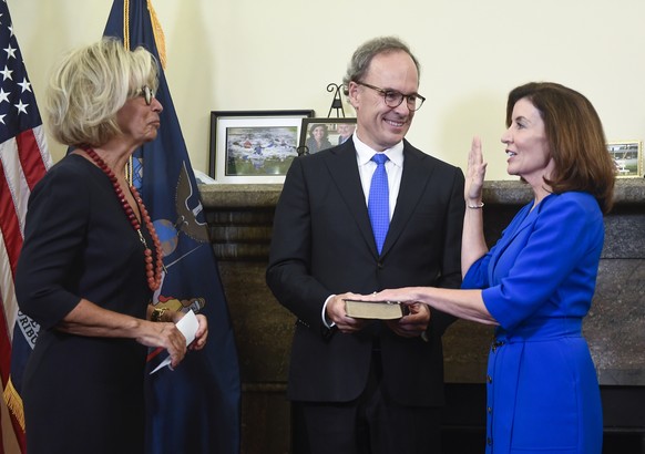 New York Chief Judge Janet DiFiore, left, swears in Kathy Hochul, right, as the first woman to be New York&#039;s governor while her husband Bill Hochul holds a bible during a swearing-in ceremony in  ...