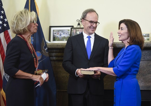 New York Chief Judge Janet DiFiore, left, swears in Kathy Hochul, right, as the first woman to be New York&#039;s governor while her husband Bill Hochul holds a bible during a swearing-in ceremony in  ...