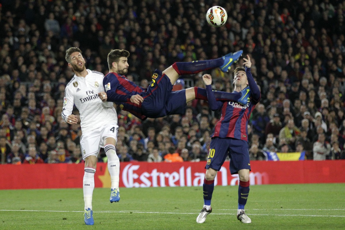 FILE- In this Sunday, March 22, 2015 file photo, Barcelona's Gerard Pique kicks the ball with Real Madrid's Sergio Ramos, left, and Barcelona's Lionel Messi, right, during a Spanish La  ...
