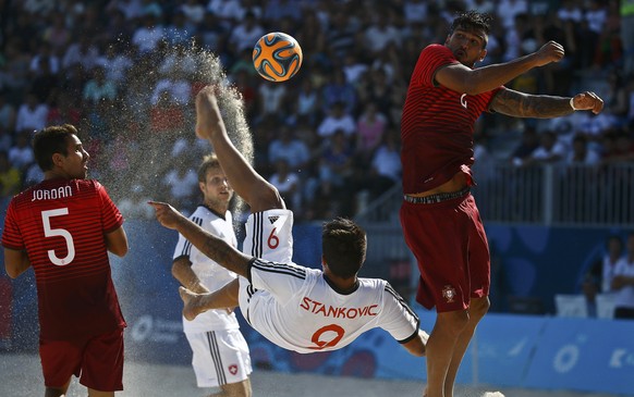 Dejan Stankovic (C) of Switzerland kicks the ball next to Jordan Santos (L) and Rui Coimbra of Portugal during their group stage beach soccer match at the 1st European Games in Baku, Azerbaijan, June  ...