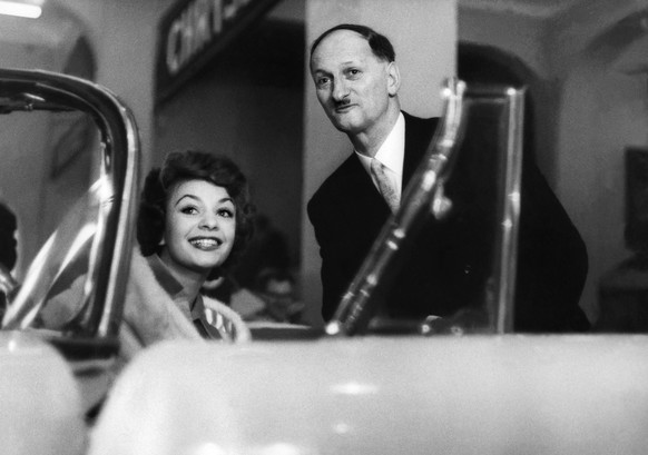 Bundespraesident Paul Chaudet (1904-1977) posiert am Eroeffnungstag des 29. Internationalen Autosalons in Genf mit einem Fotomodel hinter einem amerikanischen Automodell, aufgenommen 1959. (KEYSTONE/S ...