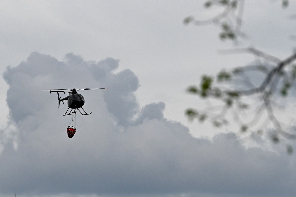 epa12939112 A helicopter equipped with a water bucket responds to a forest fire near Osuchy Village, eastern Poland, 07 May 2026. Hundreds of firefighters are taking control over the fire that has bee ...