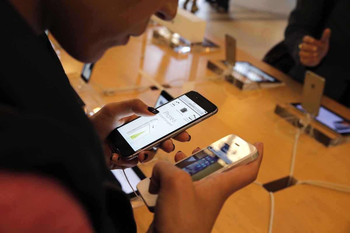 FILE - In this Sept. 19, 2014 file photo, a customer checks out the new iPhone 6 at an Apple store in Paris. Apple's iPhones and iPads are getting free software updates Wednesday, Sept. 16, 2015, ...
