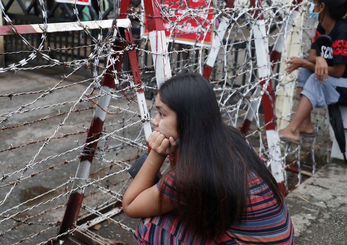 epa09530245 A woman sits near the barricade as she waits for the released of her family member outside the Insein prison in Yangon, Myanmar, 18 October 2021. Myanmar's junta chief Min Aung Haling ...