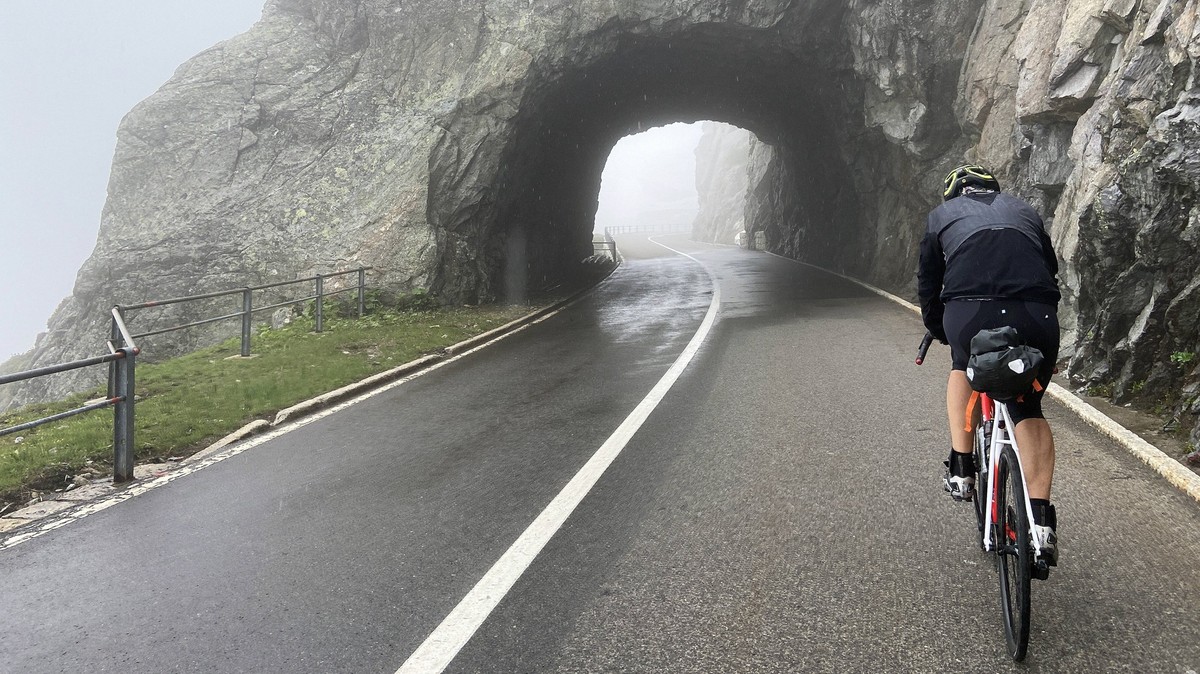Rennradfahrer auf dem nebligen Sustenpass in den Schweizer Alpen, der die Kantone Uri und Bern verbindet, Schweiz. *** Racing cyclist on the misty Susten Pass in the Swiss Alps, which connects the can ...