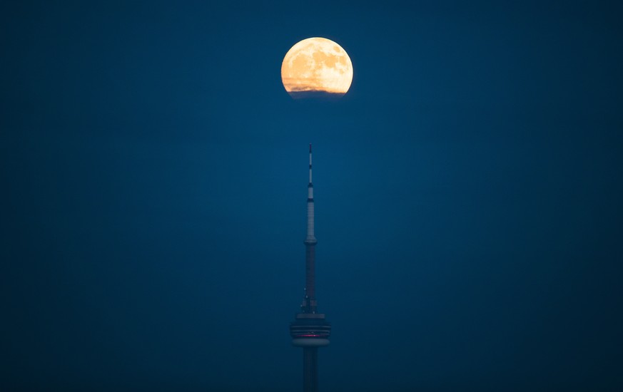 The moon rises over the CN Tower and skyline in Toronto, Ontario, Saturday, Dec. 2, 2017. The Dec. 3 full moon will be the first of three consecutive supermoons. The two will occur on Jan. 1 and Jan.  ...