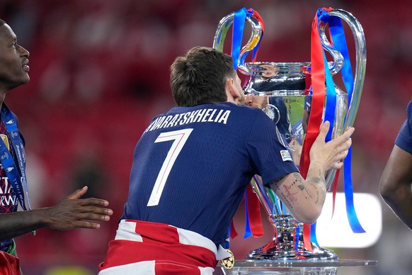 PSG's Khvicha Kvaratskhelia kisses the trophy celebrating after winning the Champions League final soccer match between Paris Saint-Germain and Arsenal in Budapest, Hungary, Saturday, May 30, 202 ...