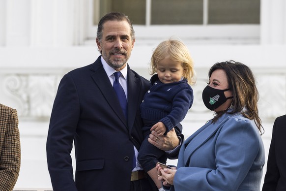 epa09598144 Hunter Biden (L) holds his son Beau (C) as they watch US First Lady Jill Biden (not pictured) receive the official 2021 White House Christmas Tree on the North Portico of the White House i ...