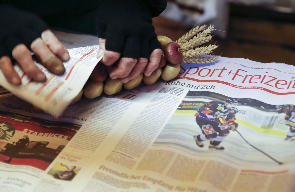 Eine Verkaeuferin packt Zwiebeln in eine alte Ausgabe der Berner Zeitung, waehrend dem traditionellen "Zibelemaerit" am Montag, 23. November 2015 in Bern. Der Zibelemaerit findet am vierten  ...