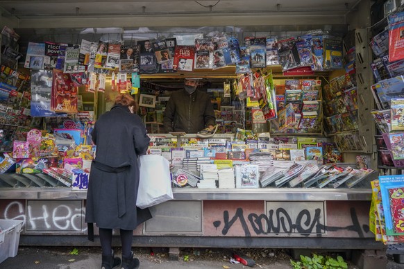 Armando Alviti, 71, stands inside his newspaper kiosk as he serves a client, in Rome, Friday, Dec. 4, 2020. In Italy, which has the world&#039;s second-oldest population, many people in their 70s and  ...