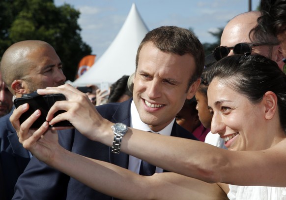 epa06048706 French President Emmanuel Macron (L) poses for a selfie during a visit to a site on the Pont Alexandre III in Paris, France, 24 June 2017. The French capital is transformed into a giant Ol ...