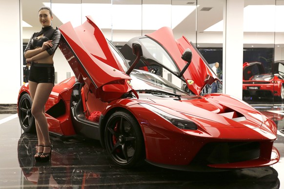 epa05654660 (FILE) An April 30, 2015 file photo shows a model posing next to a Ferrari LaFerrari hybrid sports car at a Dream Car Show in Beijing city, China.  According to media reports on December 1…