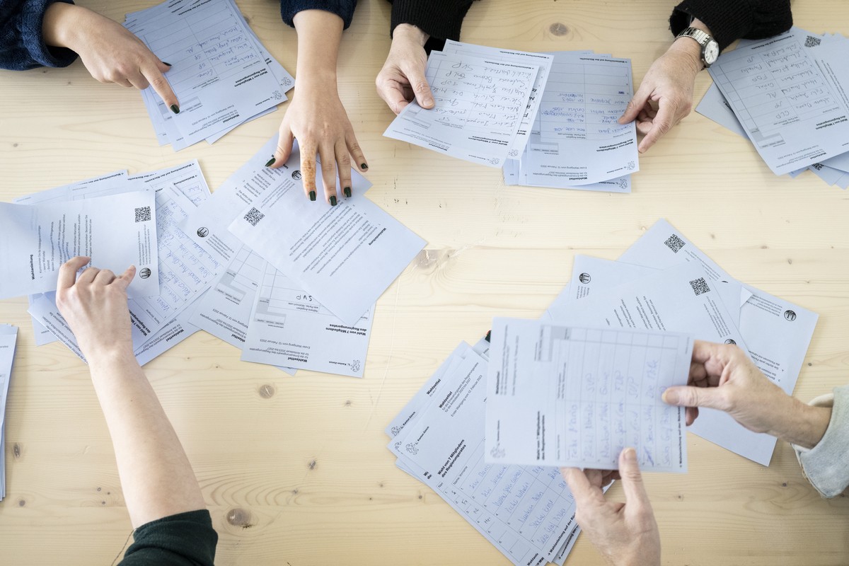 Freiwillige Mitarbeiter helfen beim Auslesen der Abstimmungsunterlagen zur Regierungs- und Kantonsratswahlen 2023 im Schulhaus Aemtler, aufgenommen am Sonntag, 12. Februar 2023, in Zuerich. (KEYSTONE/ ...