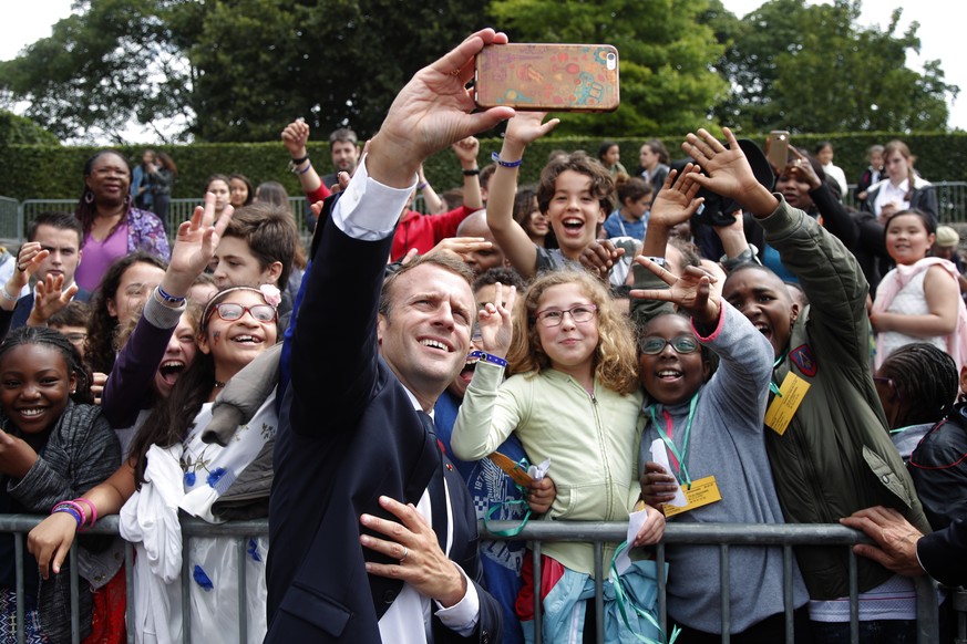 epa06818866 French President Emmanuel Macron takes selfies with children during a ceremony marking the 78th anniversary of late French General Charles de Gaulle&#039;s resistance call of June 18, 1940 ...