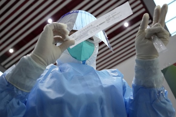 An Olympic worker in protective gear prepares to take a swab sample for a COVID-19 test at the Beijing Capital International Airport ahead of the 2022 Winter Olympics, Tuesday, Feb. 1, 2022, in Beijin ...