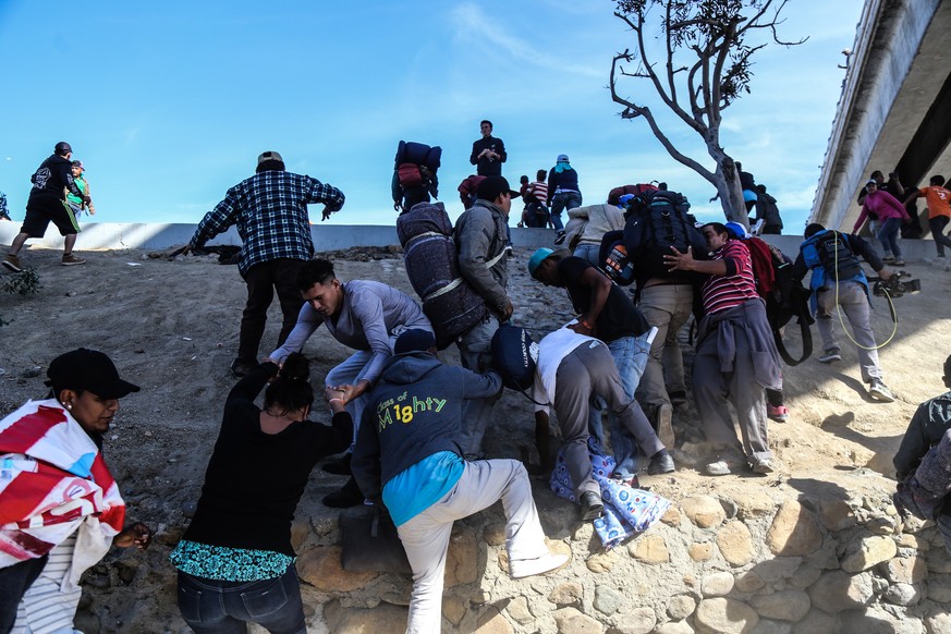 epa07190142 A group of people try to cross El Chaparral border crossing, in the city of Tijuana, in the state of Baja California, Mexico, 25 November 2018. A group of migrants from the caravan of Cent ...