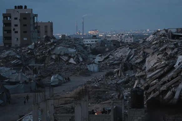 Palestinians displaced by the Israeli air and ground offensive on the Gaza Strip stand surrounded by destroyed buildings during the dusk in an area in Gaza City, Monday, June 2, 2025. (AP Photo/Jehad  ...