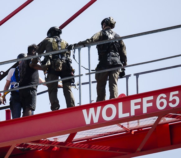 Einsatzkraefte der Polizei fuehren einen Mann ab nachdem er auf einem Baukran am Bahnhof Oerlikon Feuer entfachte und Gegenstaende herunterwarf, am Dienstag, 17. Mai 2022 in Zuerich. (KEYSTONE/Michael ...