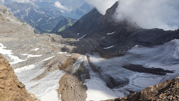View from Mount Rotstocksattel onto the dramatically melted Chlitaler firn in the cauldron between Mount Uri Rotstock and fog-shrouded Mounts Brunniblaetz and Rot Gitschen (right) above Lake Uri in Ce ...