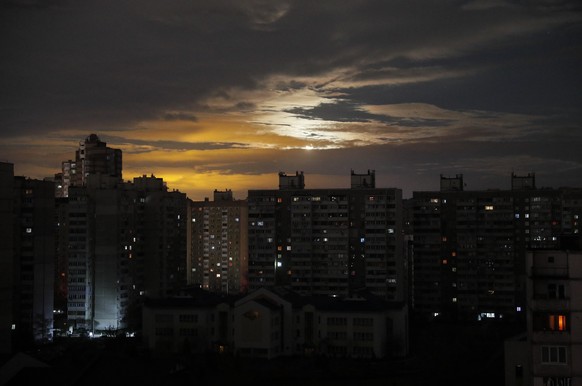 epa10300427 A view of the Moon shining through clouds behind a non-illuminated area of Kyiv (Kiev), Ukraine, 11 November 2022, as blackouts continue in the Ukrainian capital. Mayor Vitali Klitschko as ...