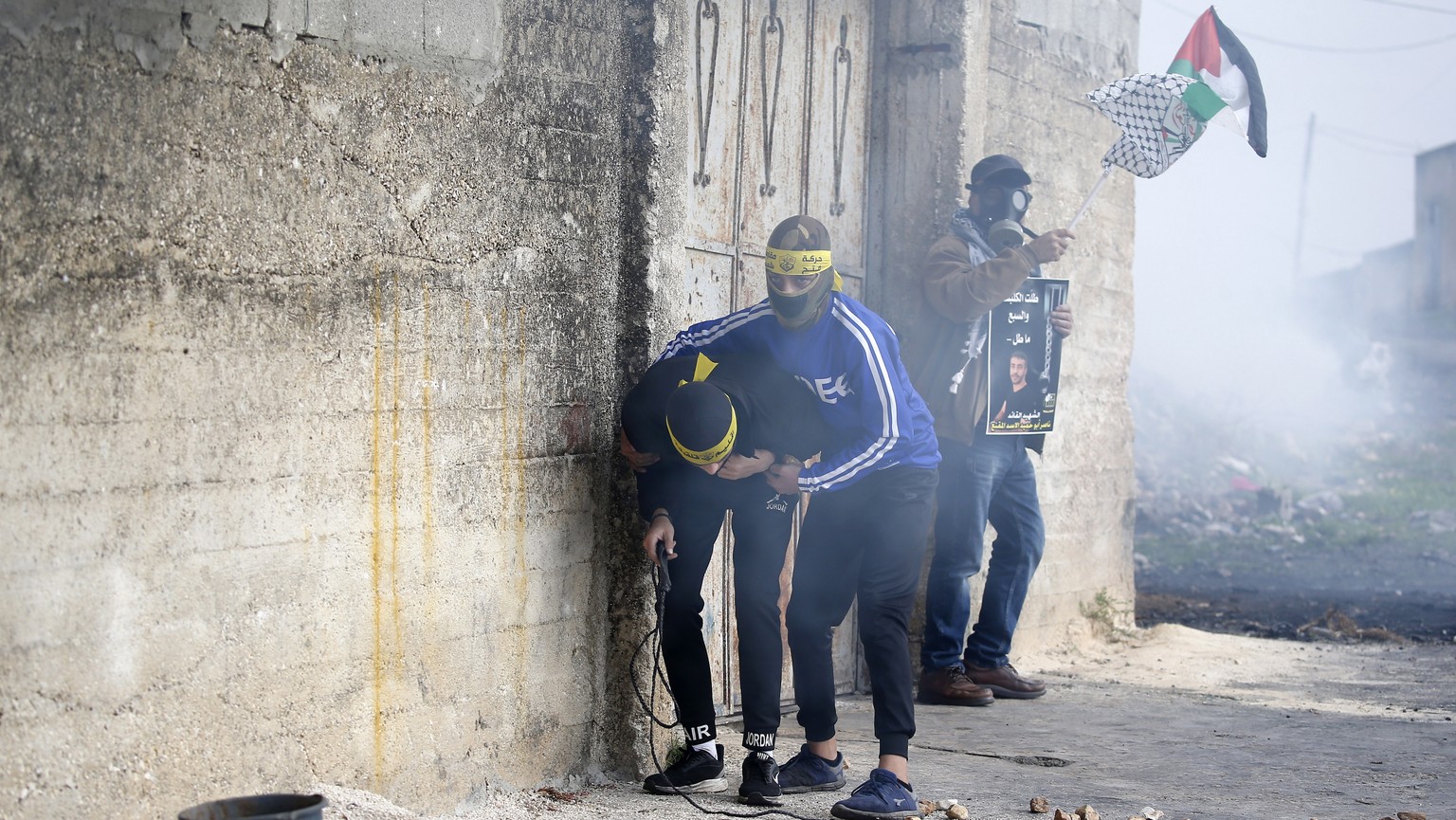 epa10377125 Palestinian protesters react to tear gas during clashes with Israeli soldiers in Kafr Qaddum village, near the West Bank city of Nablus, 23 Decemberr 2022. The clashes followed a protest a ...