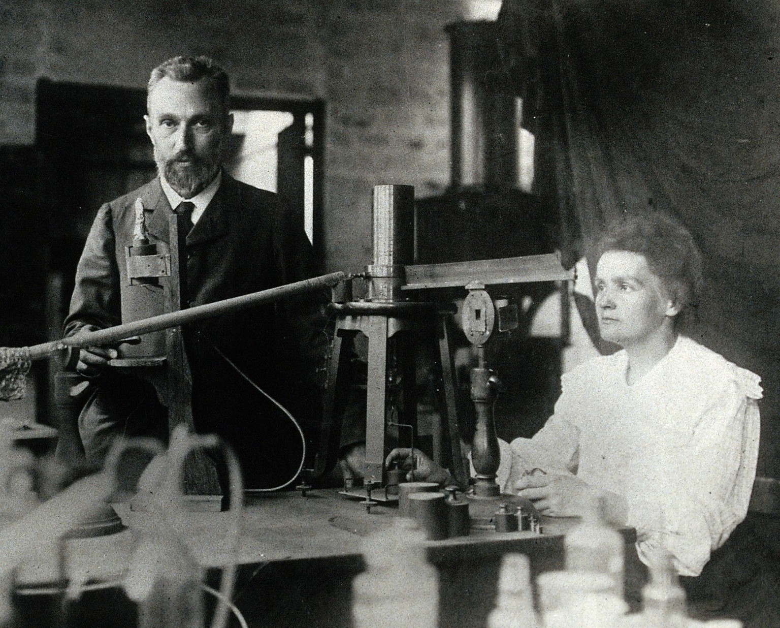 Pierre und Marie Curie in ihrem eher primitiven Labor, ca. 1904. Die Vakuumkammer der Curies war aus altem Sperrholz, aus der sie die Luft mittels Handpumpe entfernten.
