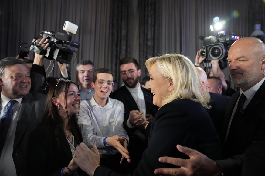 French far-right candidate Marine Le Pen shakes hands with supporters after delivering a speech at her election day headquarters in Paris, Sunday, April 10, 2022. French polling agency projections sho ...
