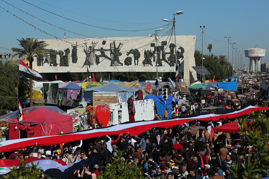 Anti-government protesters hold a huge Iraqi flag as they gather during ongoing protests in Tahrir Square in Baghdad, Iraq, Sunday, Jan. 26, 2020. (AP Photo/Hadi Mizban)