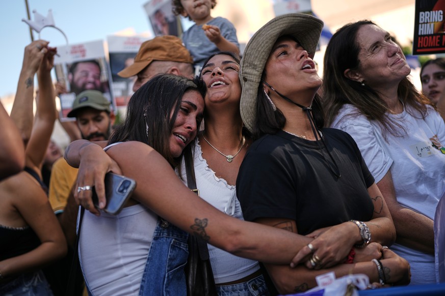 People react as they gather to watch a live broadcast of Israeli hostages released from Gaza at a plaza known as hostages square in Tel Aviv, Israel, Monday, Oct. 13, 2025. The release took place as p ...