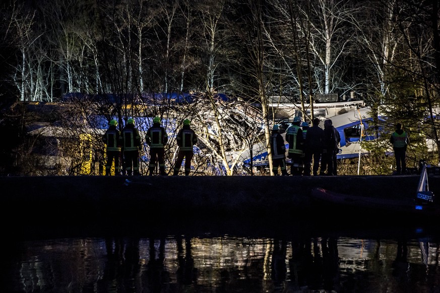 Rettungskräfte vor den verunfallten Zugwaggons.