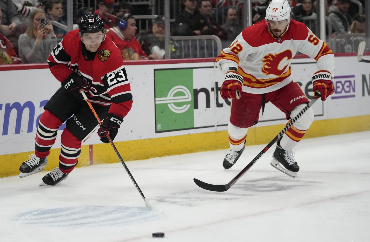 Chicago Blackhawks center Philipp Kurashev, left, and Calgary Flames defenseman MacKenzie Weegar chase the puck in the Flames&#039; end during the first period of an NHL hockey game Sunday, Jan. 8, 20 ...