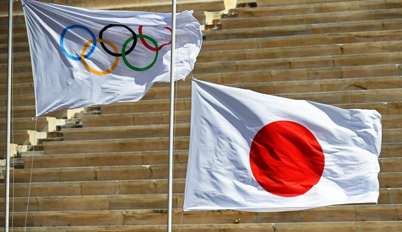 epa08318015 (FILE) - The national flag of Japan (R) is hoisted next to the Olympic flag (L) during the Olympic Flame handover ceremony for the Tokyo 2020 Summer Olympic Games at the Panathenaic Stadiu ...