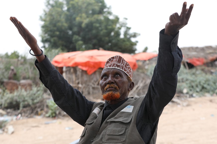 epa08305875 Muuse Aarinte, 93yrs old, chief of a nomadic village which was affected by desert locust invasion illustrates how he reacted when he first saw the locust invasion close to one of their bre ...