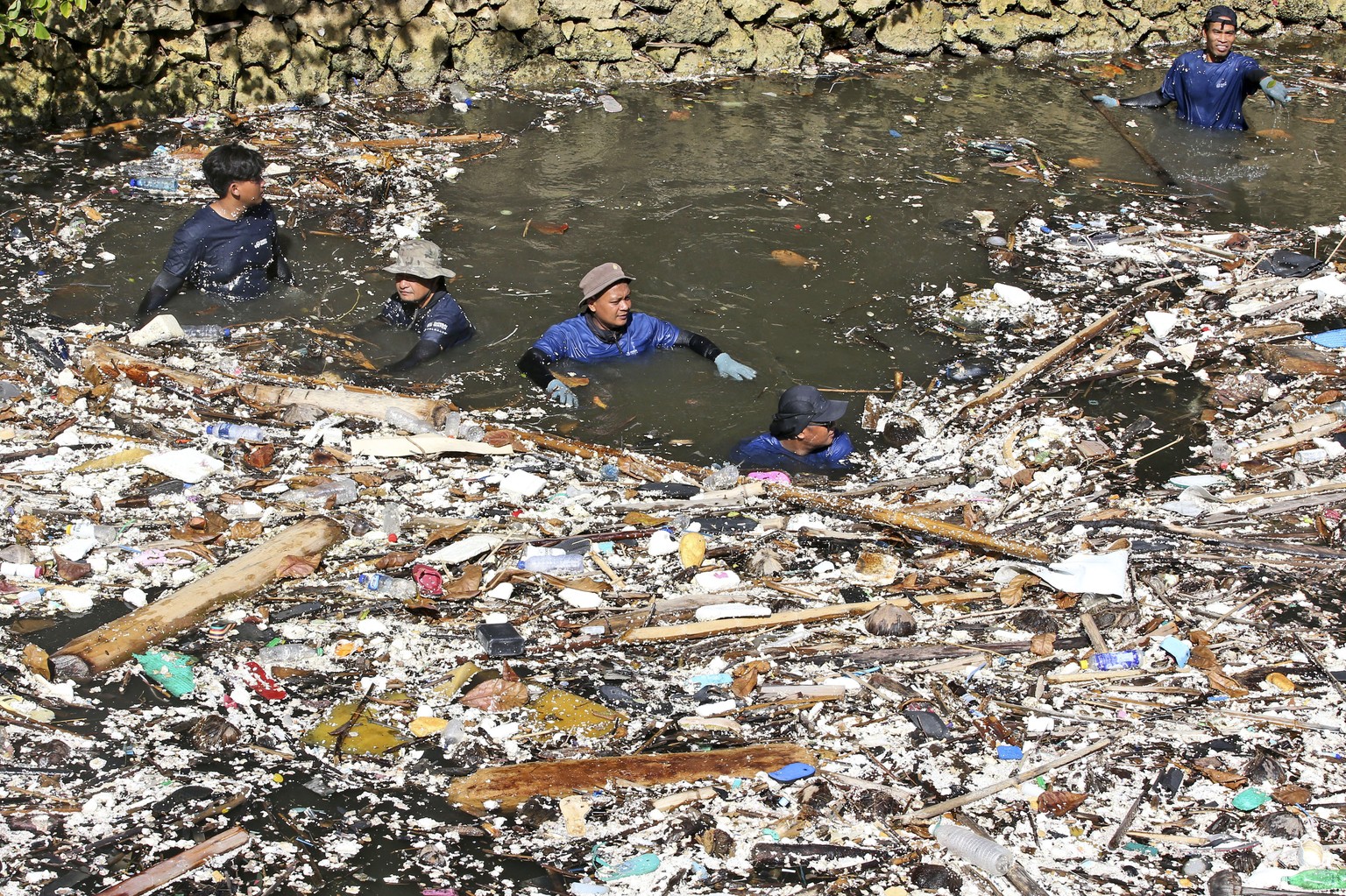 Environmental activists and volunteers pick up trash from a garbage-strewn river during a river clean up in Pecatu, Bali, Indonesia on Friday, March 22, 2024. (AP Photo/Firdia Lisnawati)