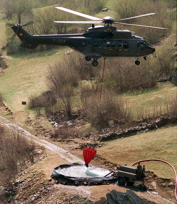 Ein Super Puma-Helikopter entlaedt Wasserbehaelter in ein Bassin inmitten der Brandherde im Misox im April 1997. Die Zusammenarbeit von zivilen Behoerden und Armee in der &quot;Operation Misox&quot; z ...